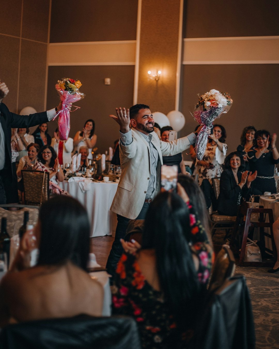 Man in blazer receives flowers at a celebratory event.