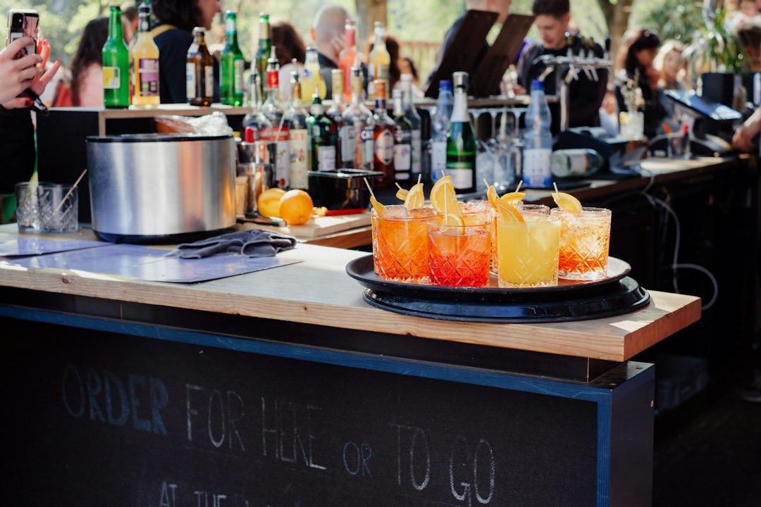 Colorful cocktails sit on a wooden bar counter.